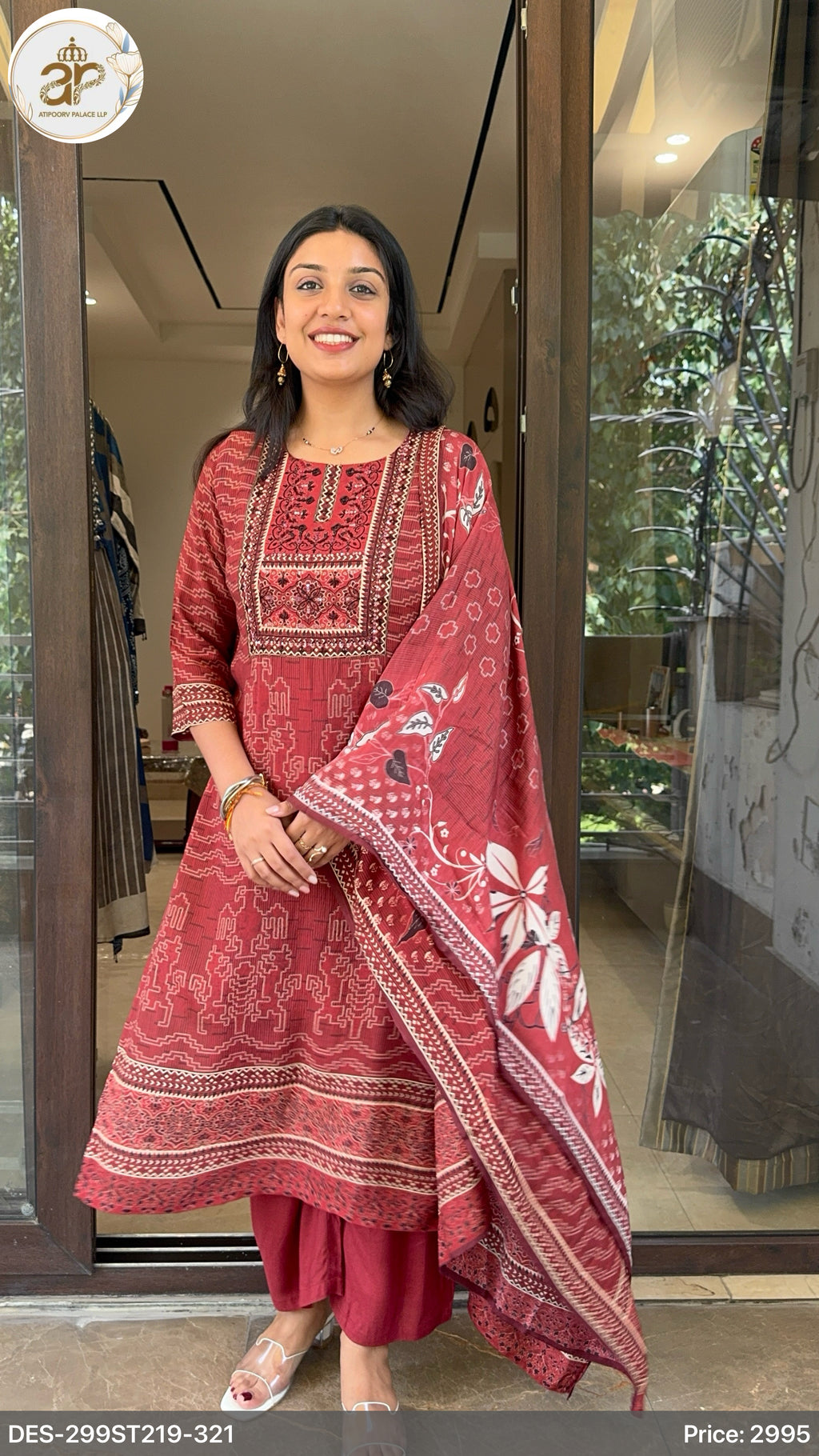 Woman wearing a red traditional outfit with floral patterns in an indoor setting.
