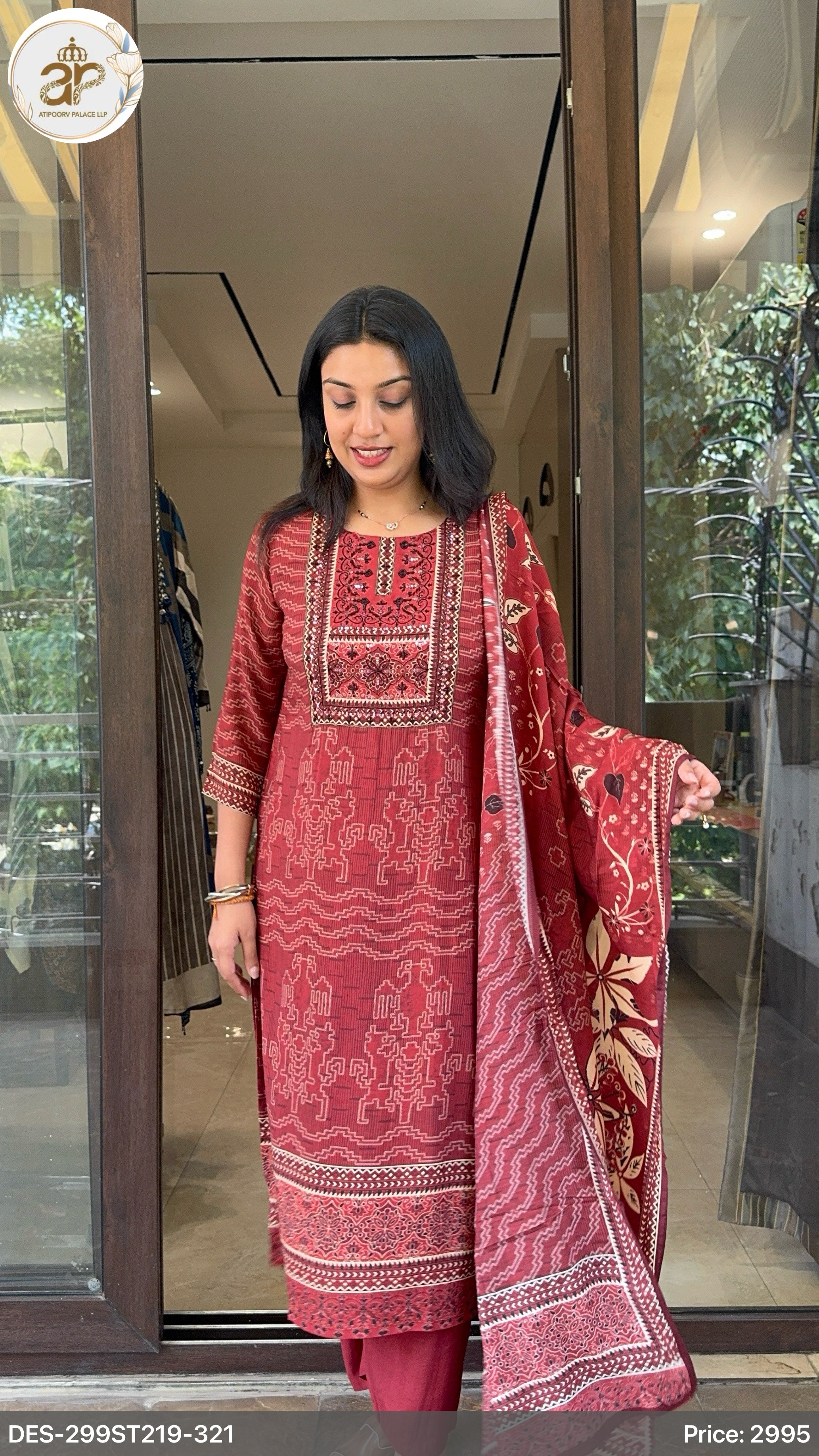 Woman wearing a red embroidered traditional outfit standing in front of a glass door.