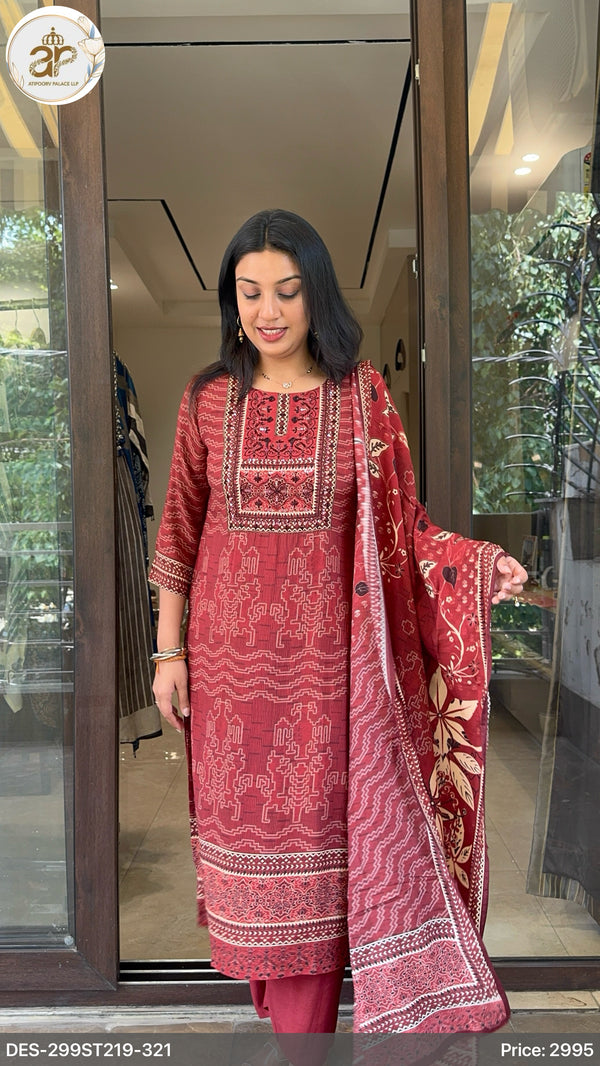 Woman wearing a red embroidered traditional outfit standing in front of a glass door.