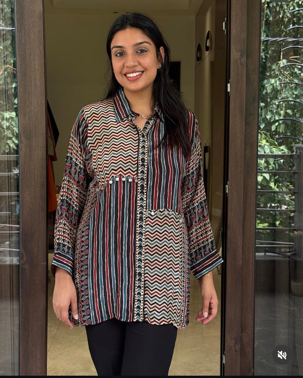 Woman wearing a patterned shirt standing in a doorway.