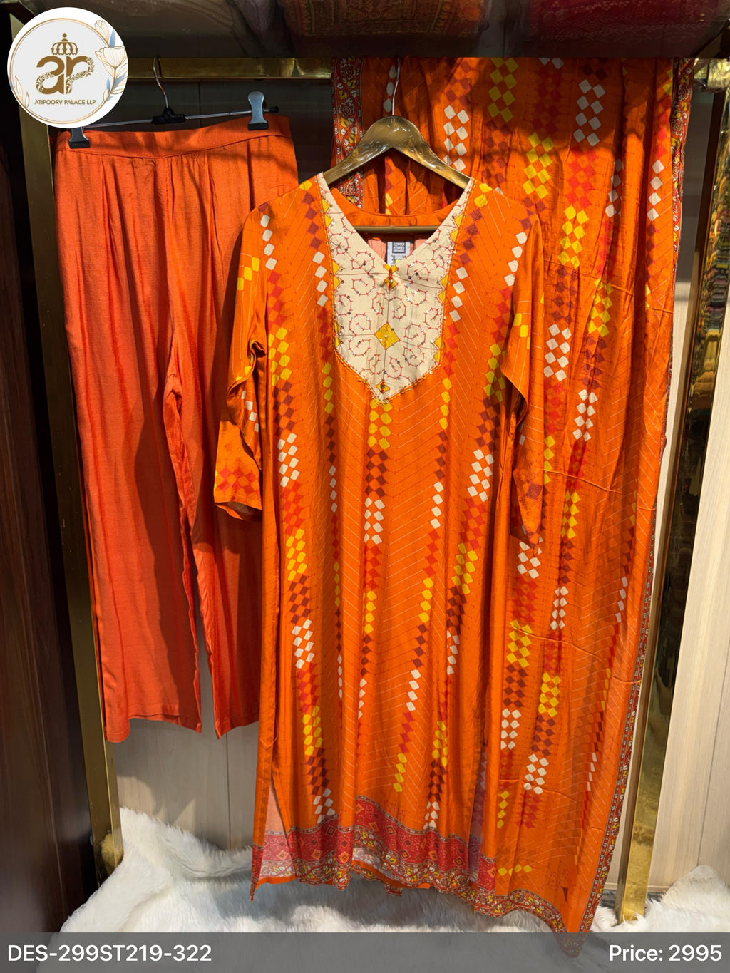 Orange traditional outfit with a patterned dress and pants on a rack.