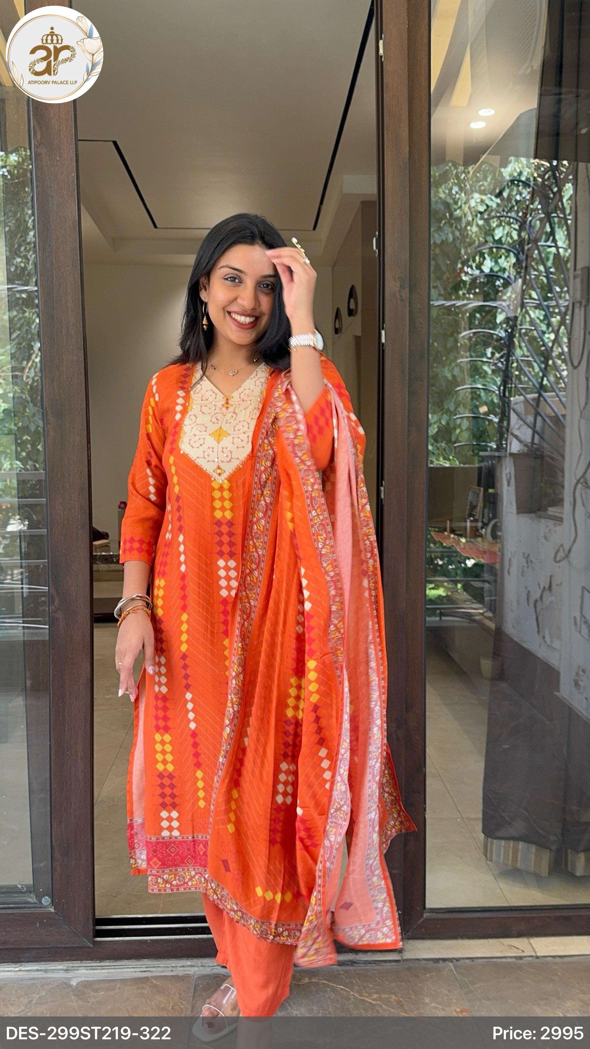 Woman in an orange traditional outfit standing in front of a glass door.